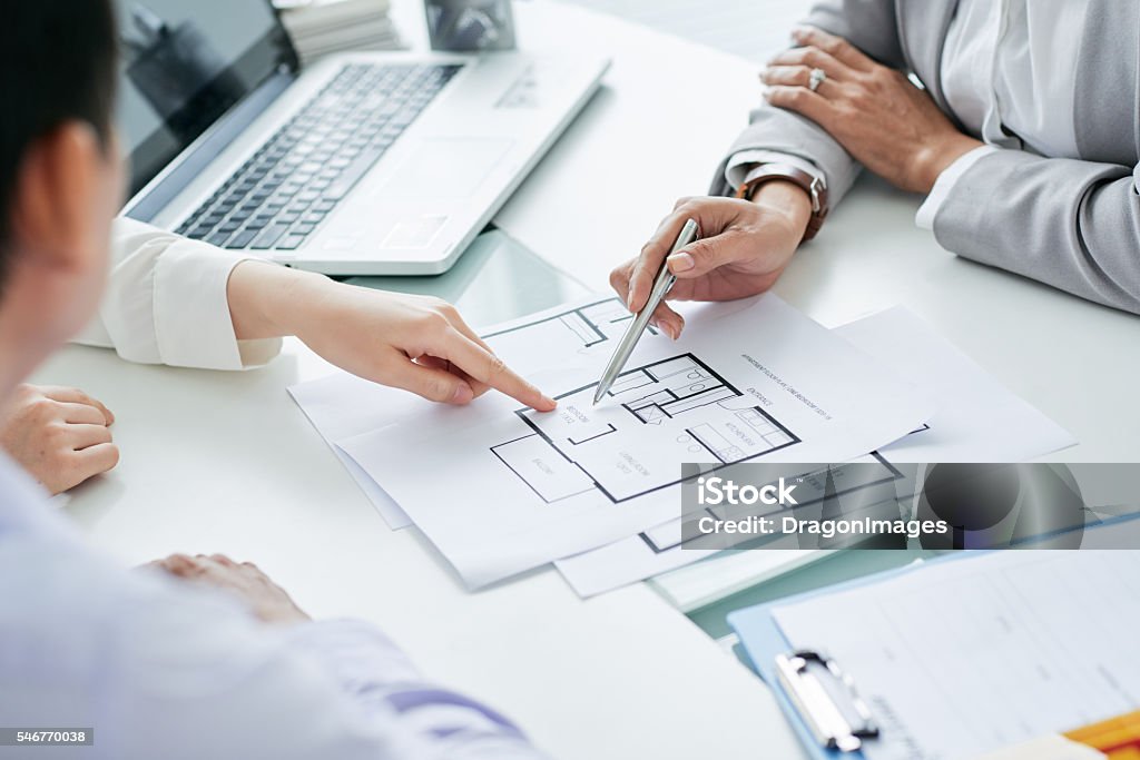 Hands of estate broker showing blueprint to investors